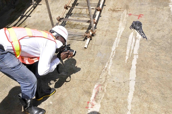 A journalist trying to take a picture of the cracked Karuma bridge sluice gates.