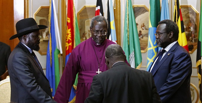 South Sudan's rebel leader Riek Machar (R) and South Sudan's President Salva Kiir (L) hold a priest's hands as they pray 