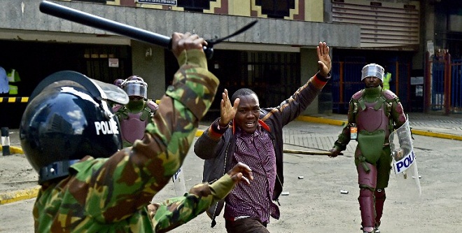 Kenyan riot police officers raise batons over a man during a demonstration of Kenya's opposition supporters in Nairobi, on May 16, 2016. Opposition protestors led by former Prime Minister Raila Odinga gathered outside the Indepedent Electoral and Boundaries Comission building to demand the dismissal of IEBC commissioners, after alleged bias towards the ruling Jubillee Alliance Party. / AFP PHOTO / CARL DE SOUZA