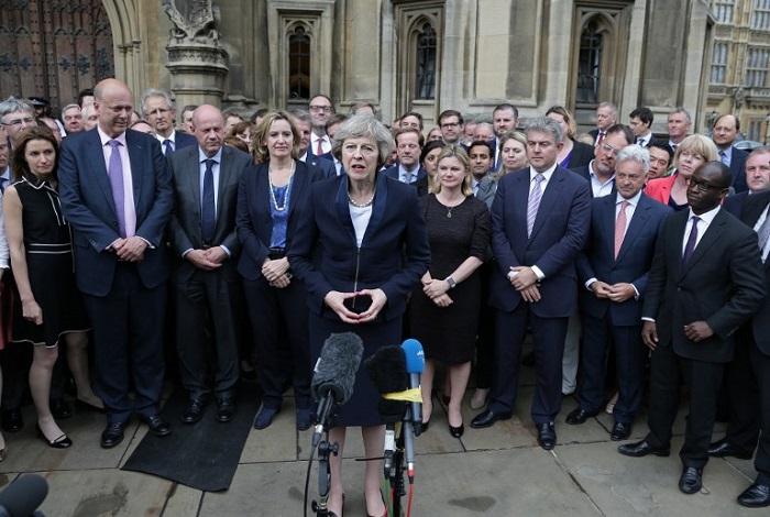 Britain's new Conservative Party leader Theresa May (C), flanked by her supporters, speaks to members of the media at The St Stephen's entrance to the Palace of Westminster in London on July 11, 2016. Theresa May will on Wednesday become the prime minister who leads Britain's into Brexit talks after her only rival in the race to succeed David Cameron pulled out unexpectedly. May was left as the only contender standing after the withdrawal from the leadership race of Andrea Leadsom, who faced criticism for suggesting she was more qualified to be premier because she had children.  / AFP PHOTO / DANIEL LEAL-OLIVAS