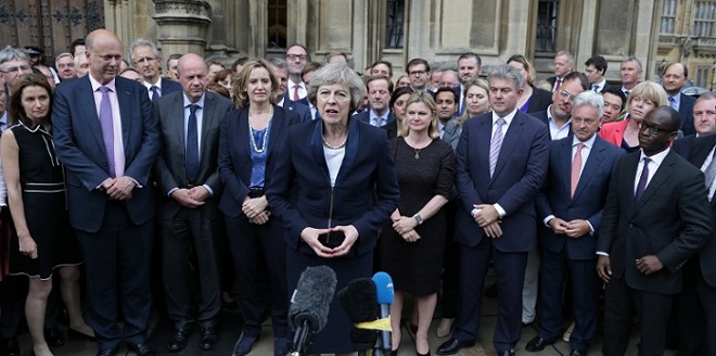 Britain's new Conservative Party leader Theresa May (C), flanked by her supporters, speaks to members of the media at The St Stephen's entrance to the Palace of Westminster in London on July 11, 2016. Theresa May will on Wednesday become the prime minister who leads Britain's into Brexit talks after her only rival in the race to succeed David Cameron pulled out unexpectedly. May was left as the only contender standing after the withdrawal from the leadership race of Andrea Leadsom, who faced criticism for suggesting she was more qualified to be premier because she had children.  / AFP PHOTO / DANIEL LEAL-OLIVAS