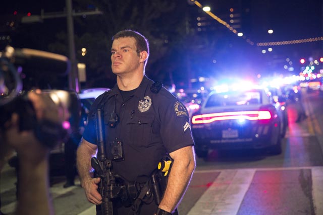 A Police officer stands guard at a baracade following the sniper shooting in Dallas on July 7, 2016. A fourth police officer was killed and two suspected snipers were in custody after a protest late Thursday against police brutality in Dallas, authorities said. One suspect had turned himself in and another who was in a shootout with SWAT officers was also in custody, the Dallas Police Department tweeted. / AFP PHOTO / Laura Buckman