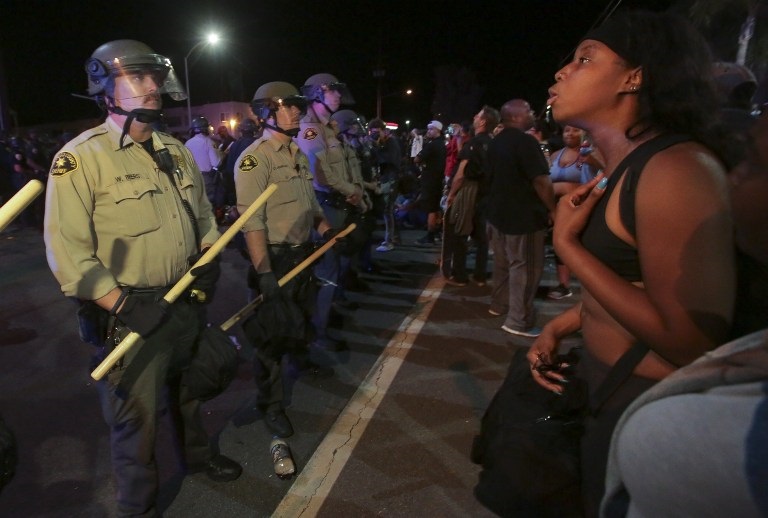 Protesters face off with police in El Cajon, a suburb of San Diego, California on September 28, 2016, in response to a police shooting the night before of Ugandan refugee Alfred Olango. Protesters marched in a California town following the fatal police shooting of an unarmed black man said to be mentally ill, as local officials urged calm and pledged a full investigation. / AFP PHOTO / Bill Wechter