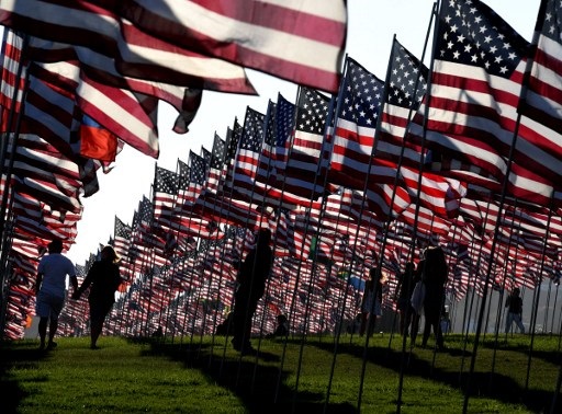 People walk amongst US national flags erected by students and staff from Pepperdine University as they pay their respects to honor the victims of the September 11, 2001 attacks in New York, at their campus in Malibu, California on September 10, 2016.  The students placed aound 3,000 flags in the ground in tribute to the nearly 3,000 victims lost in the attacks almost 15 years ago.  AFP PHOTO 