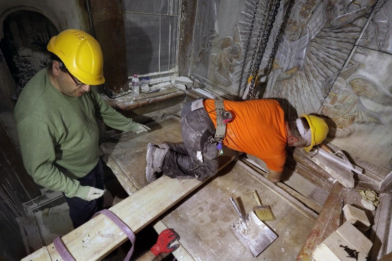 Greek preservation experts place back the marble slab stone that covered the Tomb of Jesus, where his body is believed to have been laid, after it was removed for 3 days to allow the team to do restoration works and study as part of conservation work done by the Greek team in Jerusalem on late on October 28, 2016. The experts from the National Technical University of Athens for cultural heritage preservation removed the marble slab stone that covered the original tomb since the last restoration of the edicule on 1810 by Greek architect Nikolaos Komnenos. The Church of the Holy Sepulchre in Jerusalems Old City is traditionally believed to be the site of Jesuss burial and attracts every year millions of pilgrims from all over the world. / AFP PHOTO / GALI TIBBON